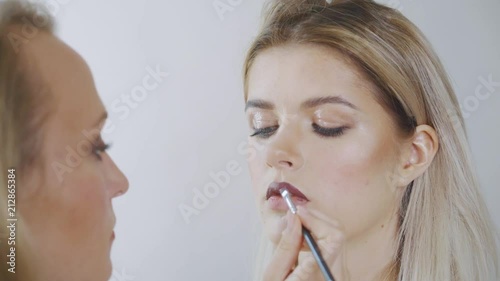 Portrait of a beautiful woman, lipstick paints a dark color, looking in the mirror. An attractive beautiful girl paints her lips with lipstick. photo