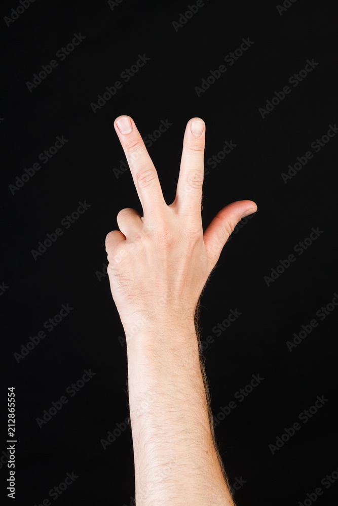Male Caucasian hand showing three fingers in front of black background