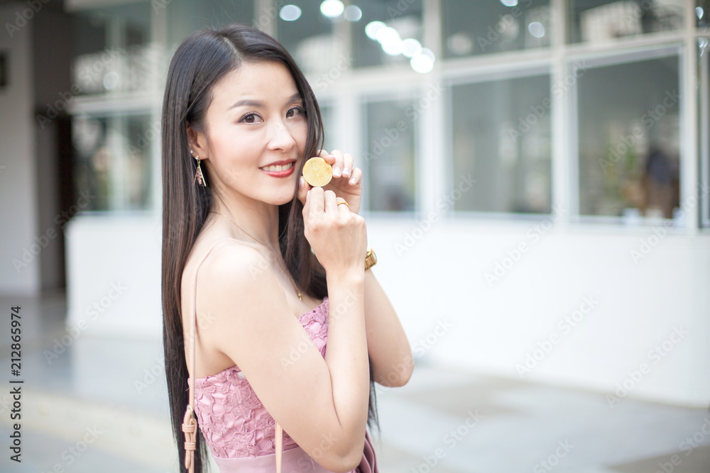 young Asia modern successful business woman holding a gold bitcoin 