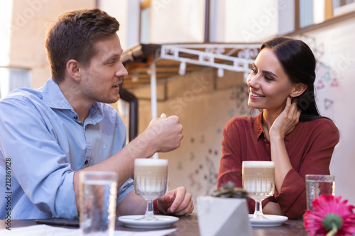 Plans for future. Handsome blonde-haired man telling his smiling loving girlfriend some plans for future