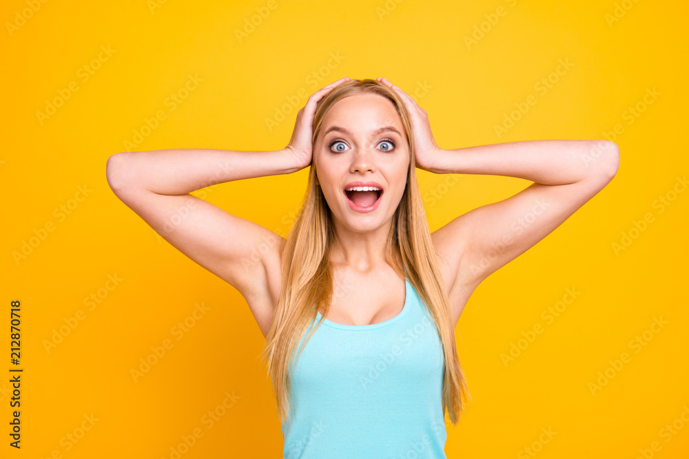 Great news! Attractive and young woman blonde touch her head with both hands from the unexpectedly happy joyous news isolated on yelow background
