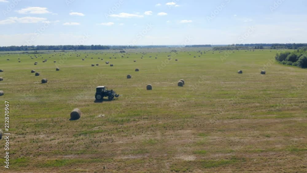 A tractor rides through a field with hay, top view.