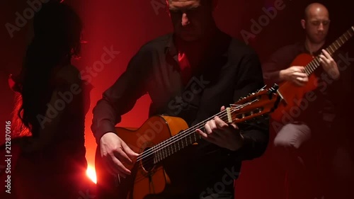 Flamenco dance performed by a professional girl next to playing guitarists music. Light from behind. smoke background. Slow motion