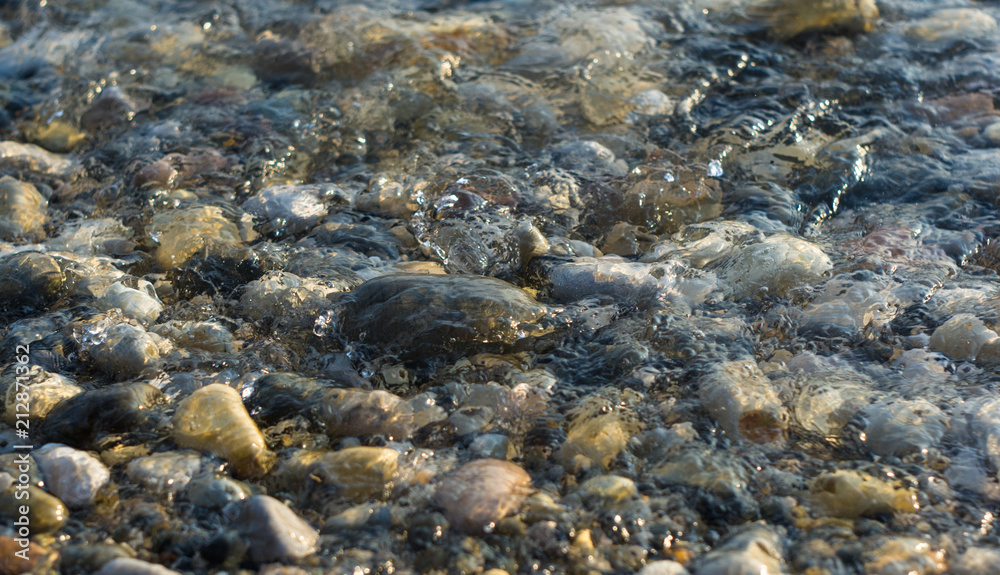 pebble stones on the sea beach, the rolling waves of the sea with foam