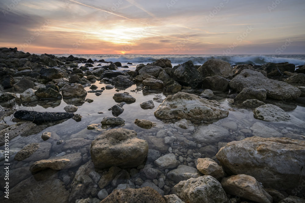 Seascape at sunrise with rocks and waves against a vibrant sky.Saint constantine and Elena beach.