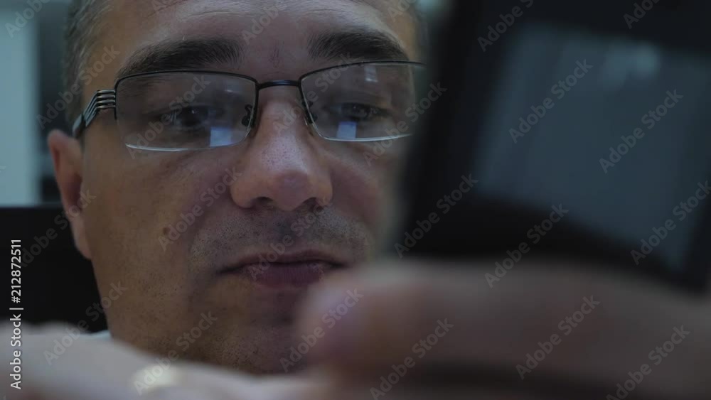 A man lying on a bed wearing glasses communicates on a smartphone A man lying on a bed wearing glasses communicates on a smartphone