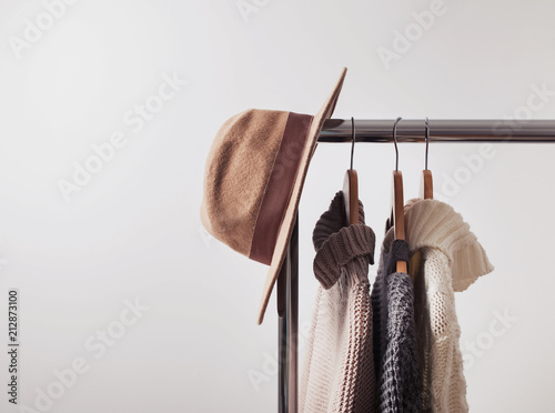 Knitted sweaters on hangers and felt hat