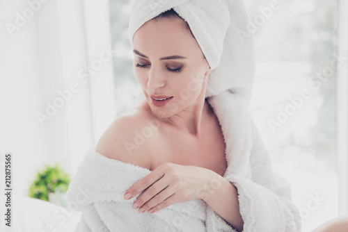Close up portrait of young attractive adorable cute smiling woman wearing bathrobe and turban showing and looking at her shoulder in white interior