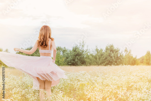 Flowers and romantic woman in the field. Lit evening sun, Beauty Romantic Girl Outdoors. Blowing Long Hair. Autumn. Glow Sun, Sunshine. Toned in warm colors 