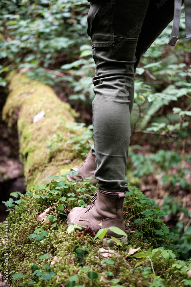 Woman's feet in travel boots on a mossy log in the forest. Travel concept. Woman's feet in travel boots on a mossy log in the forest. Travel concept.