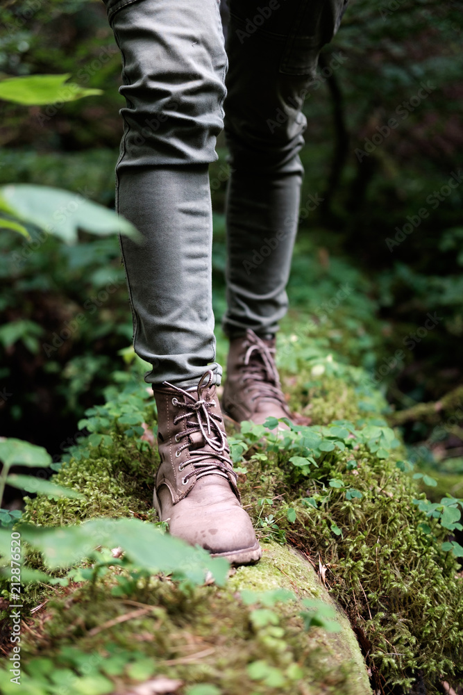 Woman's feet in travel boots on a mossy log in the forest. Travel concept. Woman's feet in travel boots on a mossy log in the forest. Travel concept.