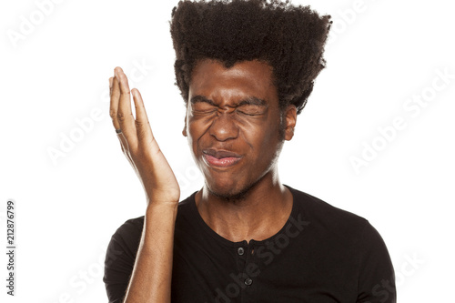 Portrait of young worried african american modern man slapped himself in the face on white background photo