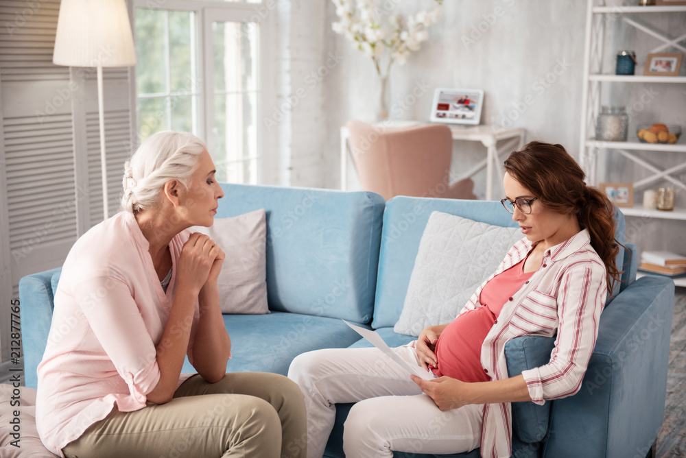 Info about childbirth. Beautiful expecting woman wearing nice black glasses reading information about childbirth Info about childbirth. Beautiful expecting woman wearing nice black glasses reading information about childbirth