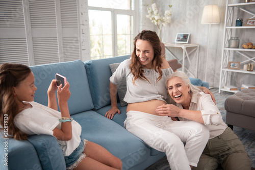 Photo with mother. Pregnant woman laughing out loud while making photo with her emotional mother