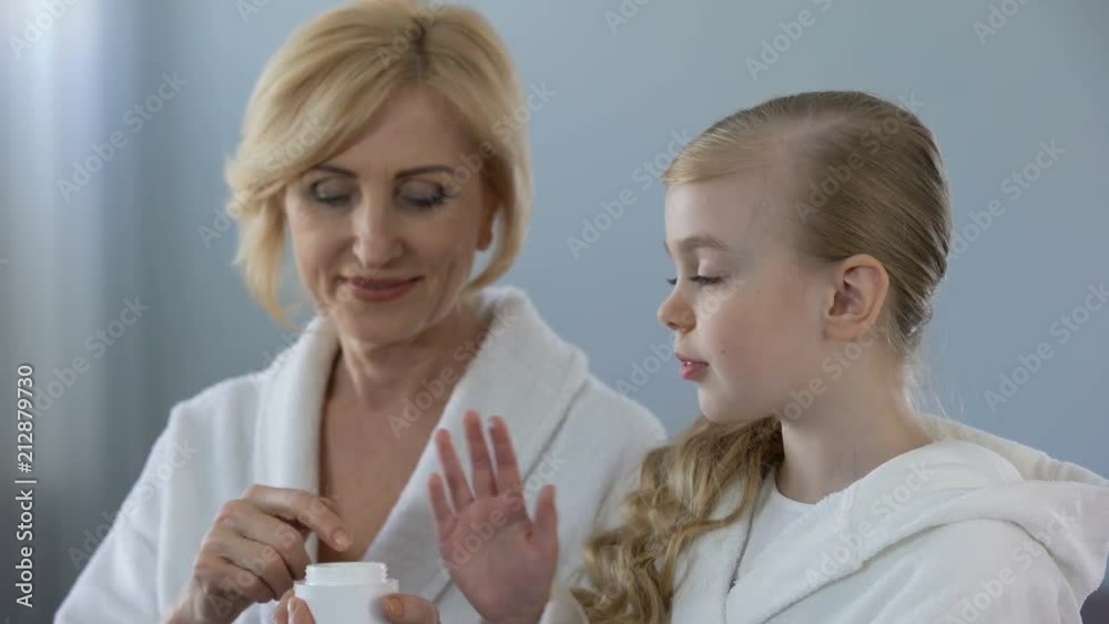 Grandmother and granddaughter applying face cream and smiling, skin care, beauty Grandmother and granddaughter applying face cream and smiling, skin care, beauty