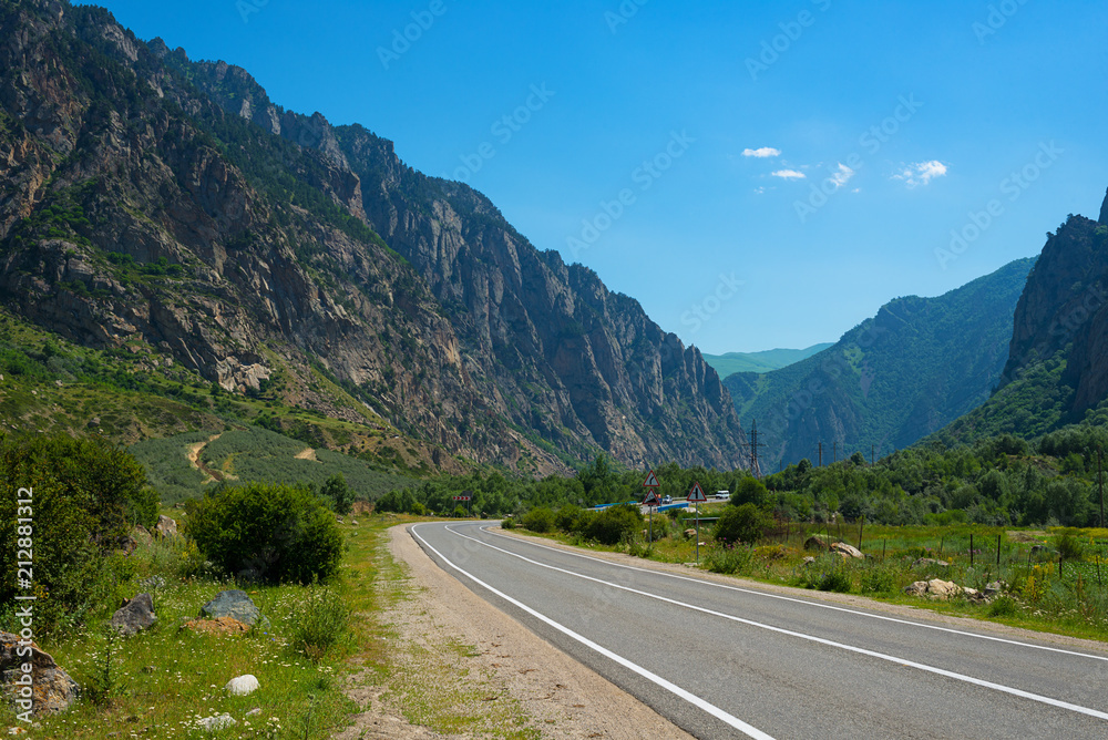 Mountain landscape, Elbrus region, Kabardino-Balkaria. In the foreground, an asphalt winding road with road markings on the background of mountains and blue sky