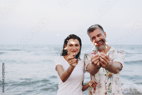 Canvas Print Couple celebrating with sparklers at the beach