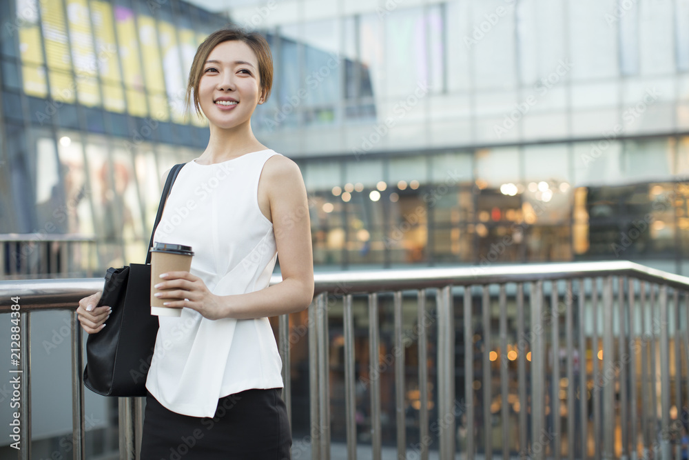 Confident young Chinese businesswoman holding a cup of coffee Confident young Chinese businesswoman holding a cup of coffee