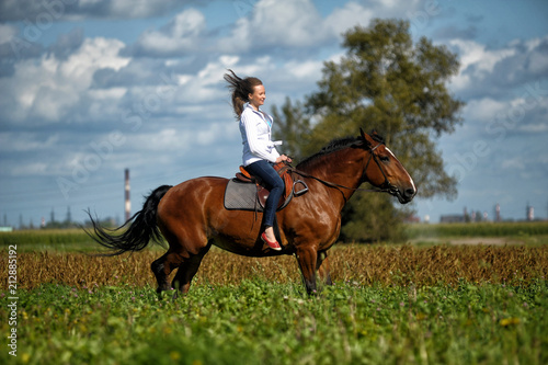blonde in a field on a brown horse photo