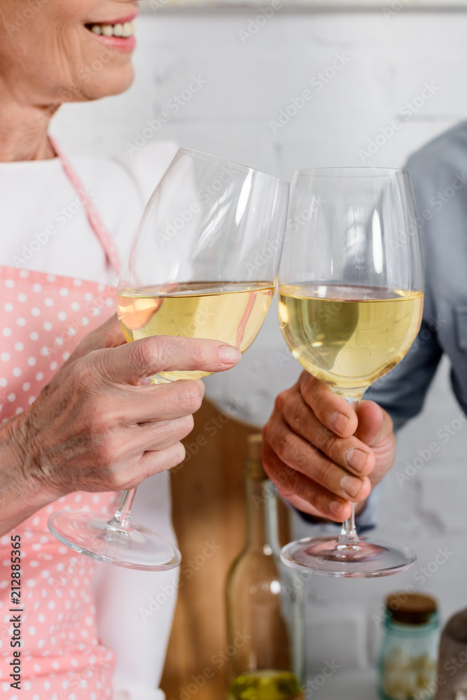 cropped shot of elederly couple clinking glasses of wine
