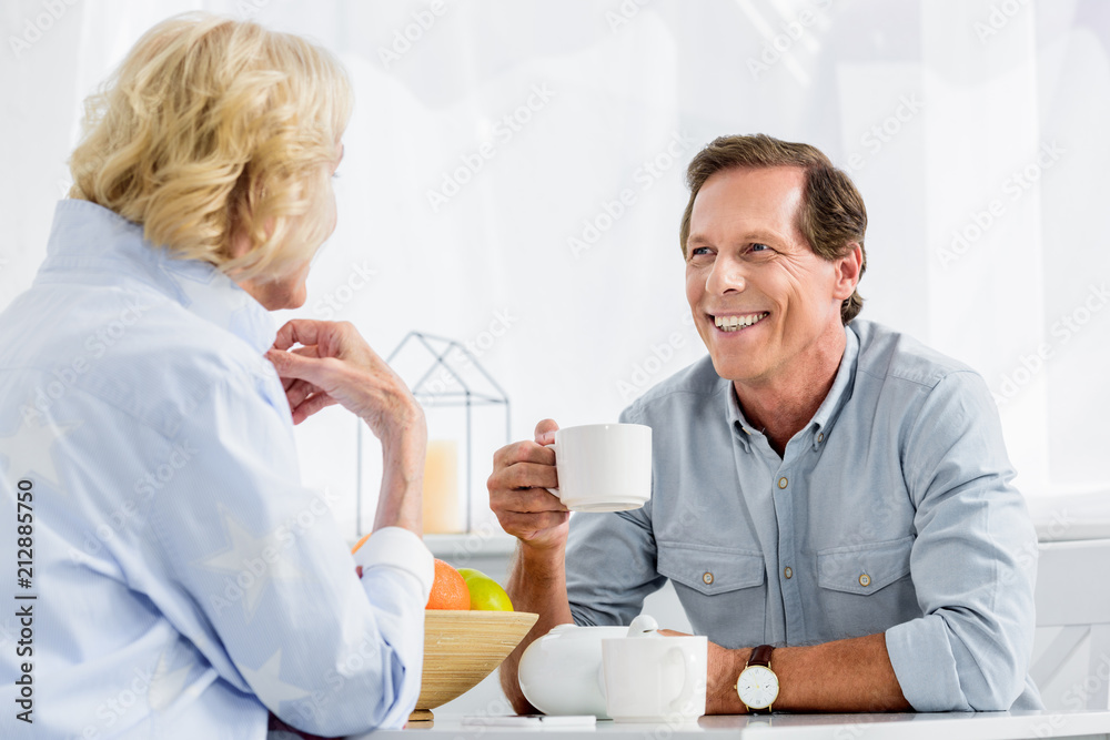 happy elderly couple drinking tea and smiling each other at home happy elderly couple drinking tea and smiling each other at home