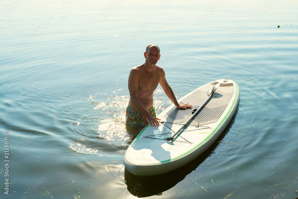Joyful man is relaxing on a SUP board and having fun