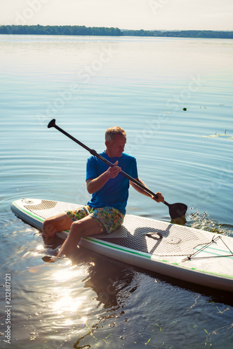 Man is relaxing on a SUP board on a large river © sanechka