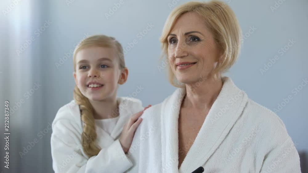 Little girl admiring her beautiful grandmother applying face powder, beauty Little girl admiring her beautiful grandmother applying face powder, beauty