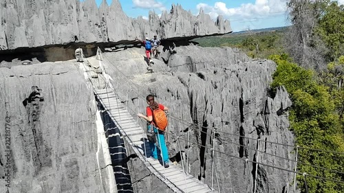 Hiker tourist walks over suspended rope bridge over gorge in Madagascar Tsingy de Bemaraha national park photo