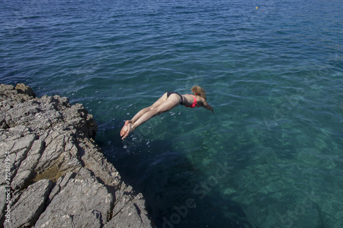 Frau im Bikini springt kopfüber ins Meer von Klippen