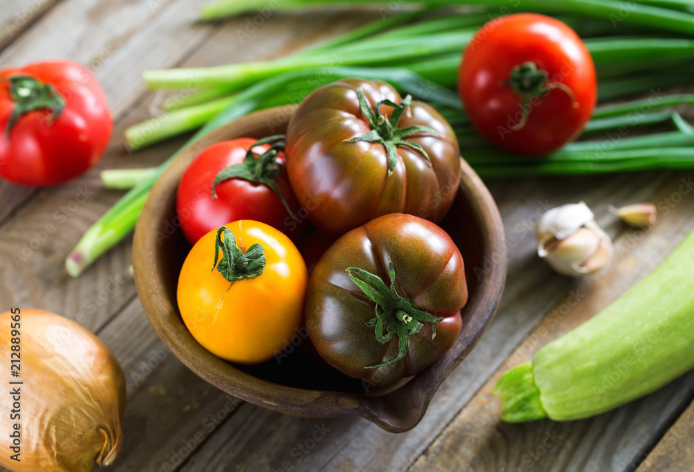 Home-grown various tomatoes and zucchini on vintage wooden boards.