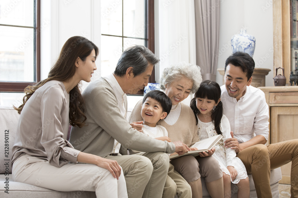 Happy Chinese family looking at photo album on sofa Happy Chinese family looking at photo album on sofa
