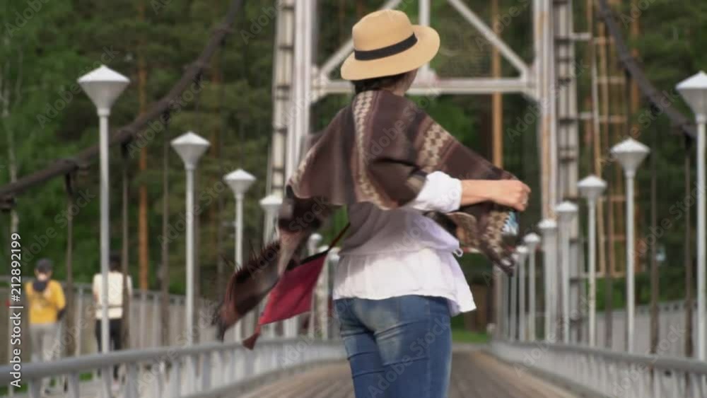 The woman the traveler goes along the cable-stayed bridge through the mountain river. The woman the traveler goes along the cable-stayed bridge through the mountain river.