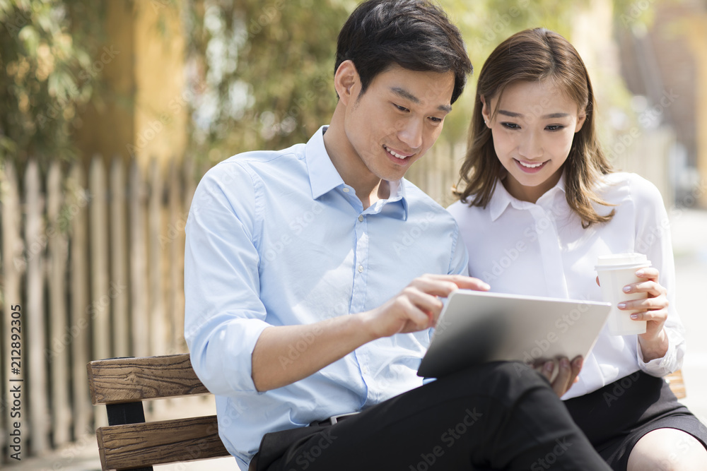 Young Chinese business people using digital tablet outdoors Young Chinese business people using digital tablet outdoors