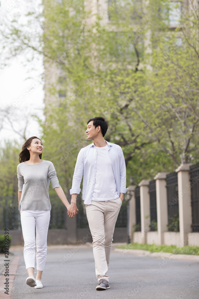 Happy young Chinese couple holding hands walking Happy young Chinese couple holding hands walking