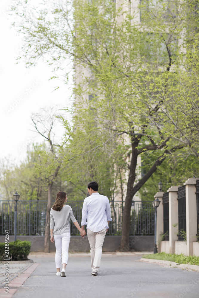 Rear view of young Chinese couple holding hands walking Rear view of young Chinese couple holding hands walking