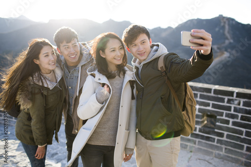 Happy young Chinese friends taking selfies on the Great Wall