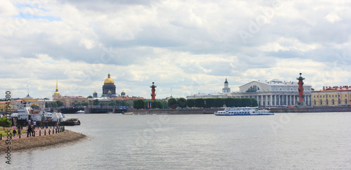 St. Petersburg City Skyline with Neva River, Saint Isaac's Cathedral, Rostral Columns, Palace Bridge in Russia. Scenic Cityscape on Gloomy Cloudy Summer Day and Tourists on Embankment Water Front.