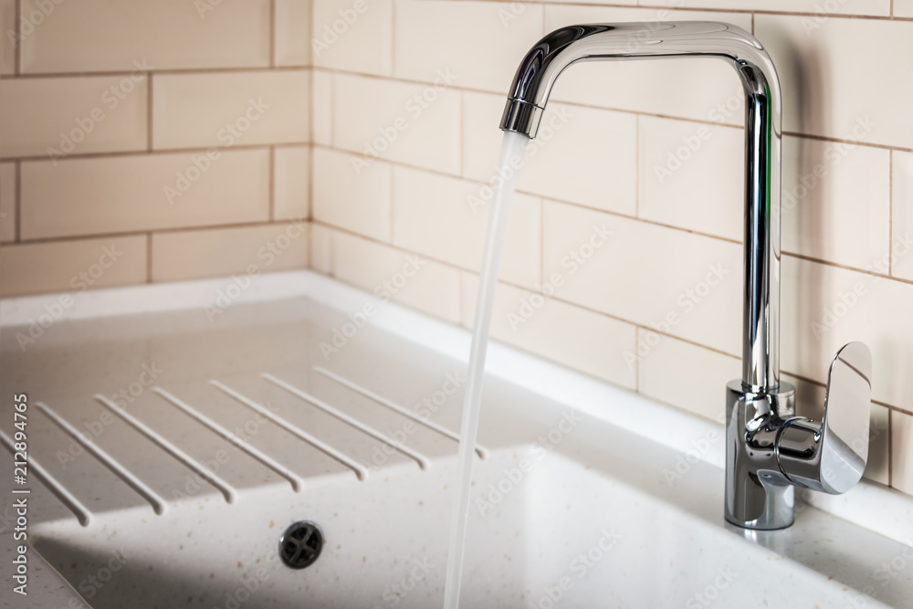 water tap in the kitchen. water flows from the tap into the sink water tap in the kitchen. water flows from the tap into the sink