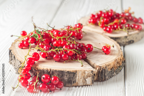 Berry crop: ripe red currants on round wooden stands on a white wooden background.