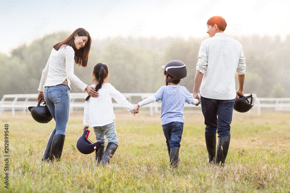 Cheerful young Chinese family walking on grassy field Cheerful young Chinese family walking on grassy field