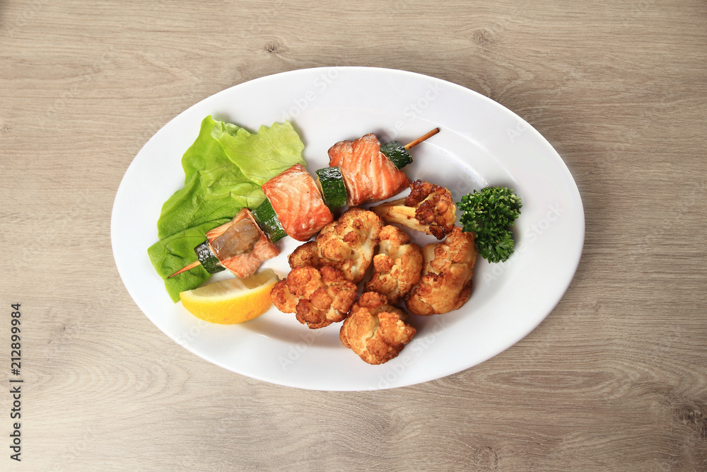 Fototapeta premium fish from the barbecue and garnish on the plate in the wooden background