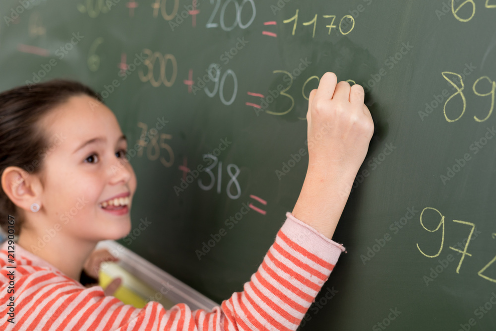 schoolgirl answering math exercice on blackboard