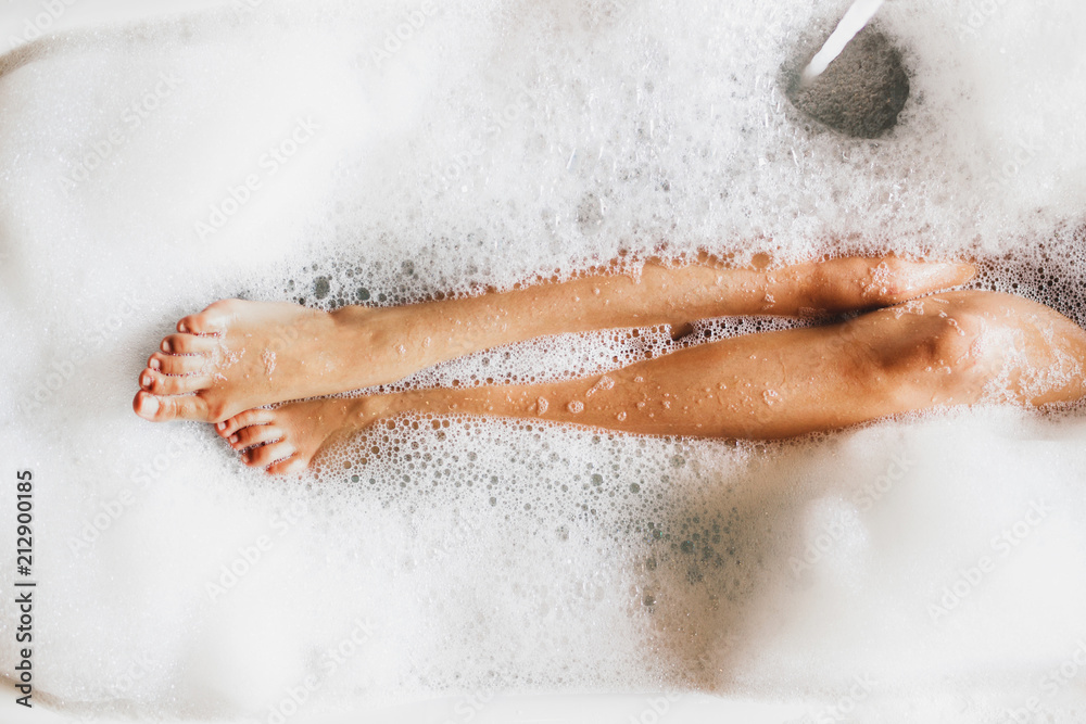 Woman legs in bath foam. Top view. Enjoying and relaxation in spa hotel - obrazy, fototapety, plakaty 