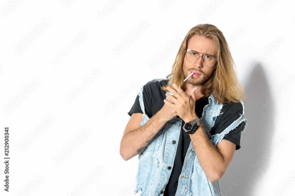 attractive young man in stylish eyeglasses smoking weed and looking at camera on white