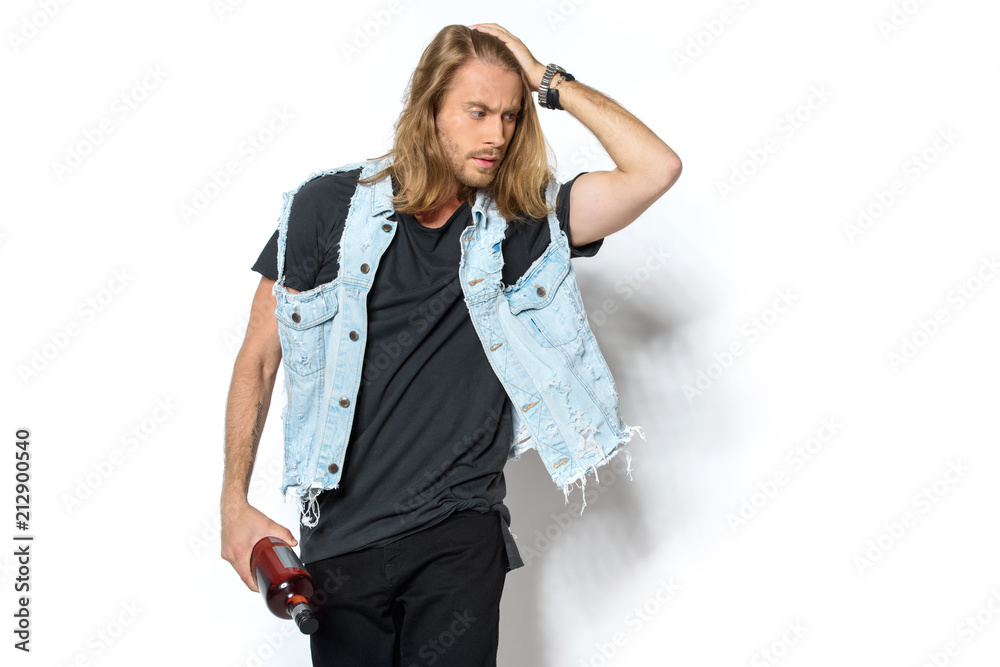 attractive young man in denim vest with bottle of rum on white attractive young man in denim vest with bottle of rum on white