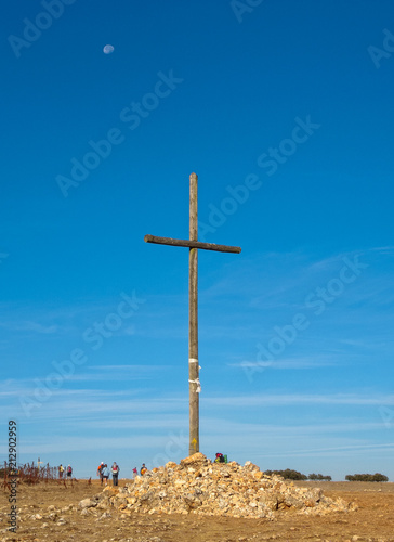 Pilgrims pass by a huge wooden cross on the Way - Alto Cruceiro, Castile and León, Spain