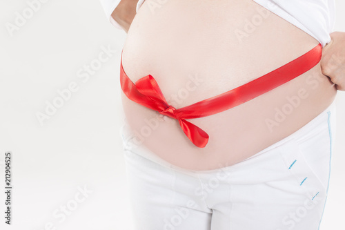 Wallpaper Mural closeup of a pregnant woman tying a red ribbon on the belly. Torontodigital.ca