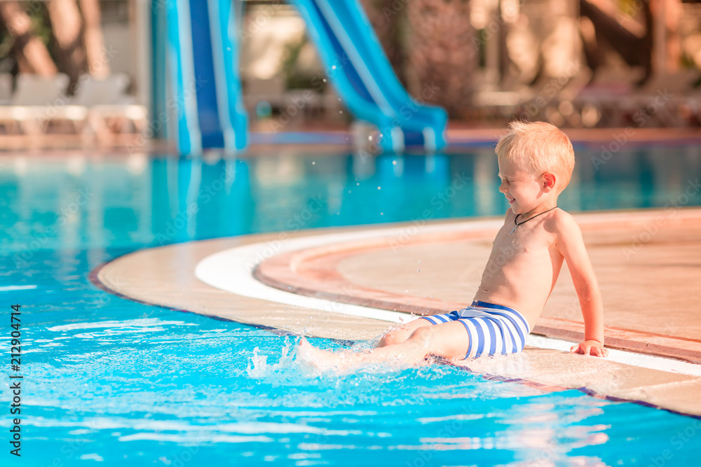 Cute little boy sitting at the pool