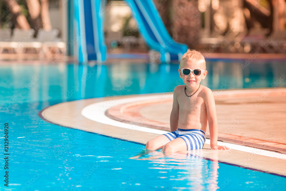 Cute little boy sitting at the pool